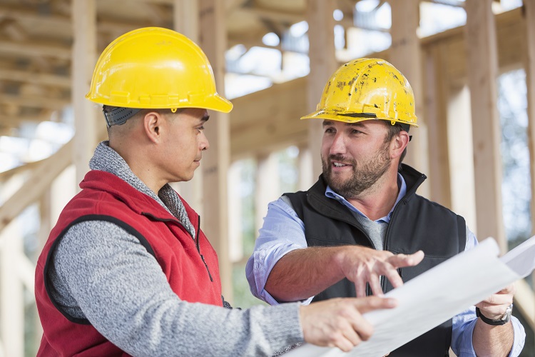 Multi-ethnic construction workers with plans, talking